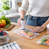 Persona usando bomba de vacío eléctrica portátil en bolsa de alimentos en cocina moderna