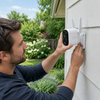 Persona instalando cámara de seguridad inalámbrica exterior en fachada de casa