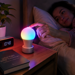 Persona tocando bombilla LED RGB recargable en mesita de noche con luz ambiental de colores